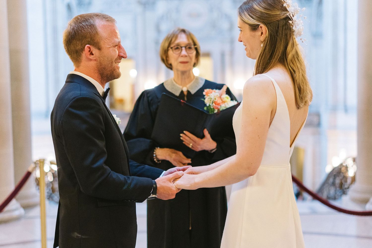 A couple exchanges vows during an intimate indoor wedding ceremony with an officiant.