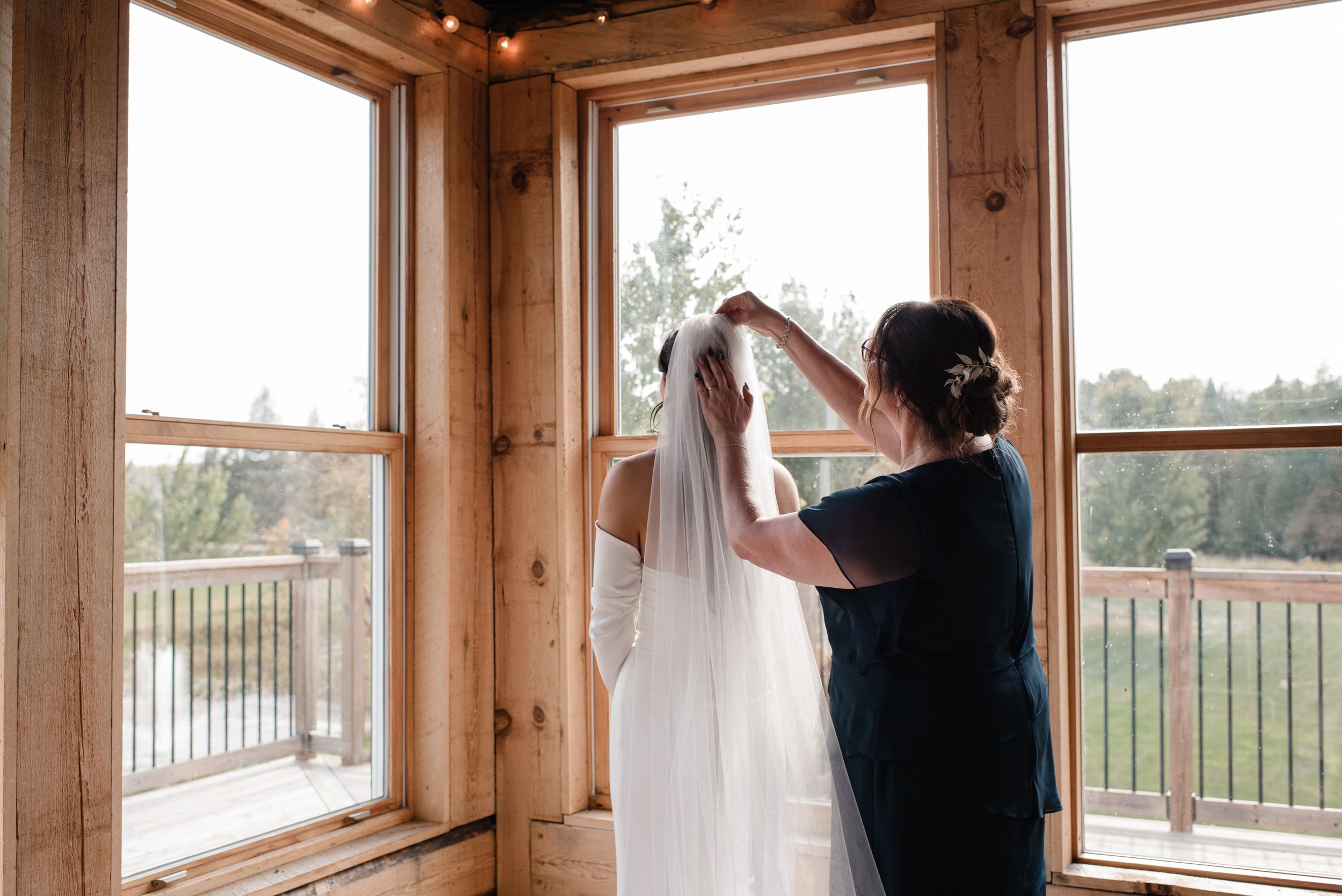 Getting ready scene showing bridal preparations near large wooden windows with scenic mountain views in background.