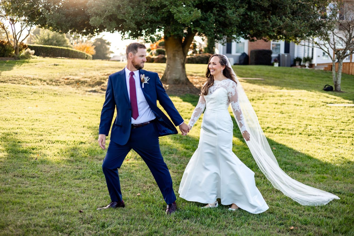 Newlyweds dancing with energy in sunlit garden setting.