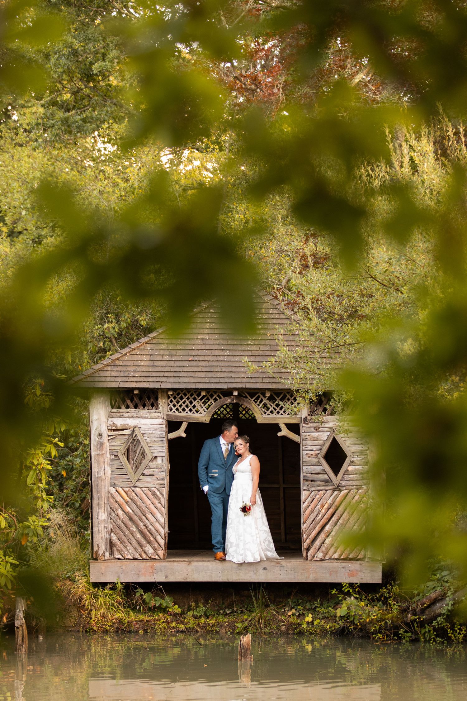 A couple shares a romantic moment overlooking a scenic hillside landscape with flowing white veil in the breeze.