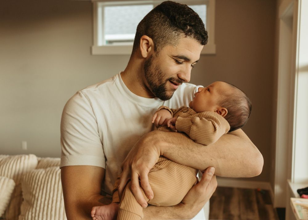 A tender moment between parent and infant in warm natural lighting.