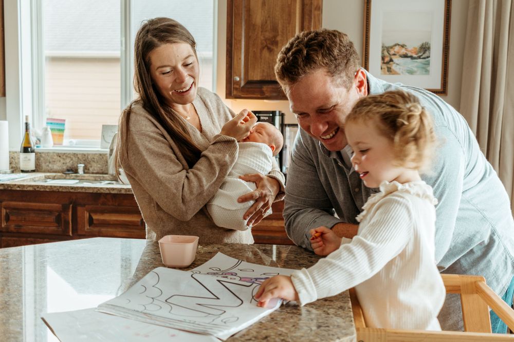 Family engaged in drawing activity together at kitchen counter in natural light.