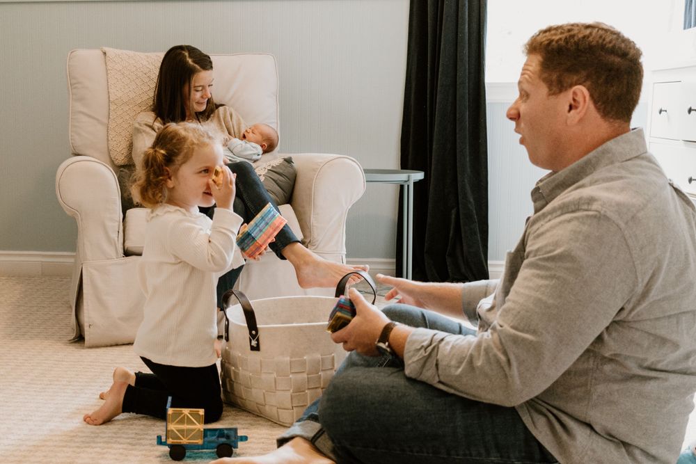 Playful family moment in living room with toys scattered on floor.