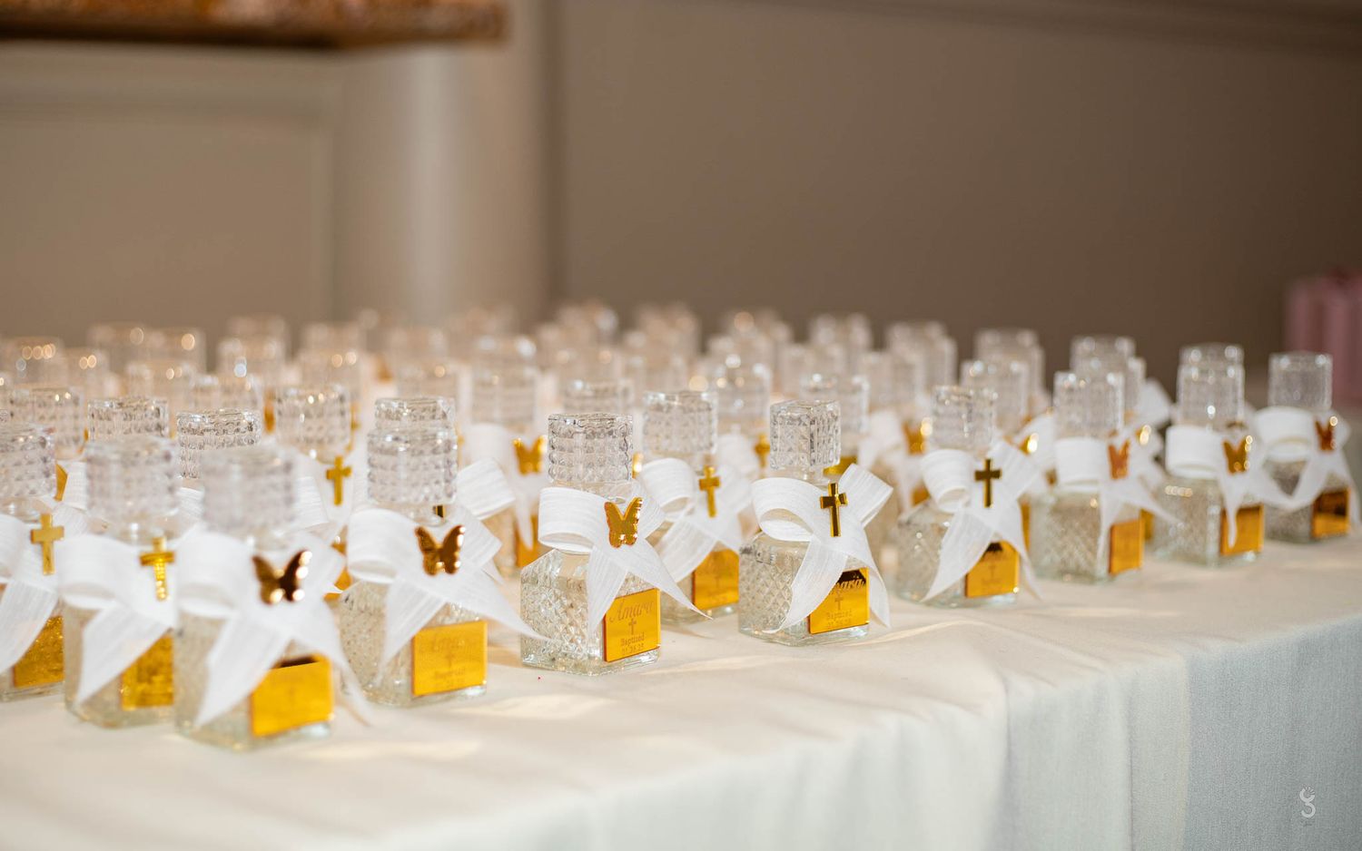 Rows of elegant wedding favor boxes with butterfly decorations arranged on white tablecloth.