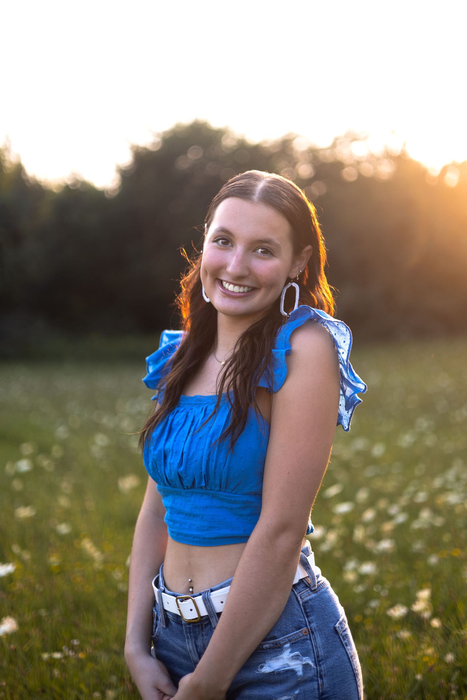 A bright blue crop top and denim outfit worn in a sunny wildflower meadow at golden hour.
