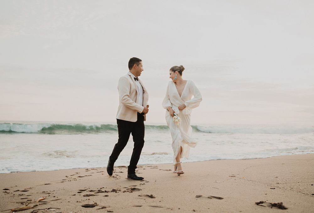 Pareja caminando y riendo en la playa durante una sesión al atardecer en Mazatlán, con un estilo natural y espontáneo.