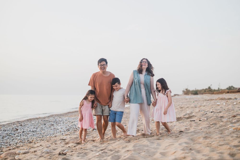 A family walks together along a serene beach during golden hour.
