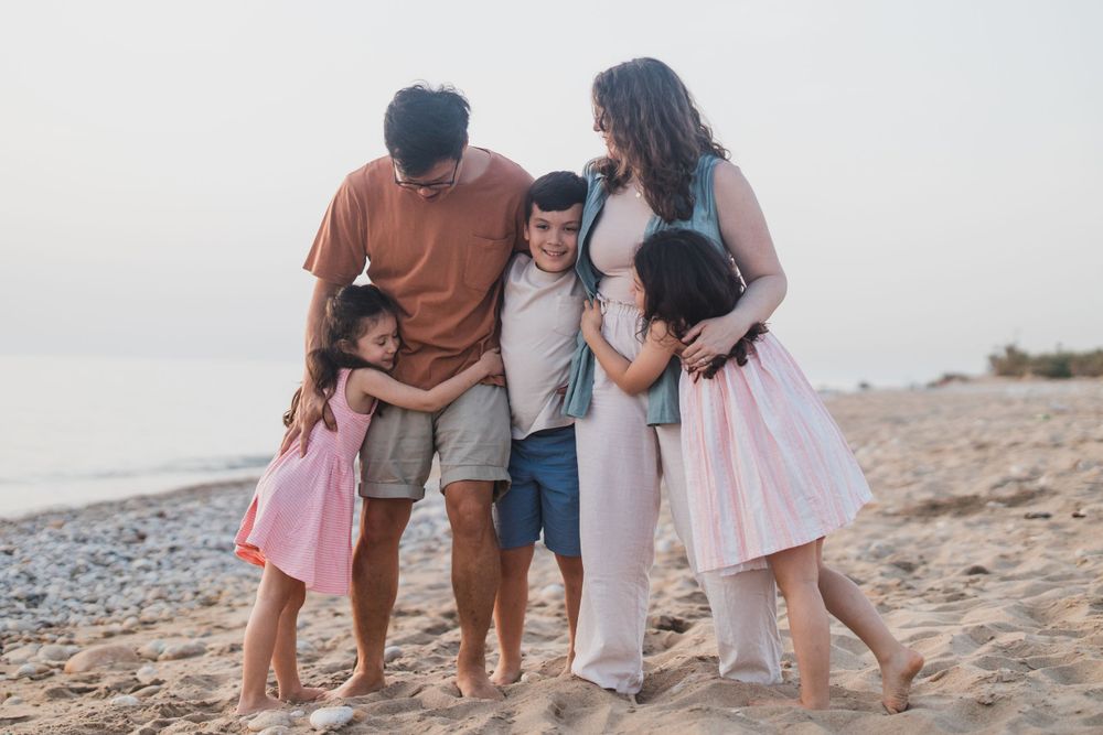 Family sharing an intimate moment together on a beach at sunset.