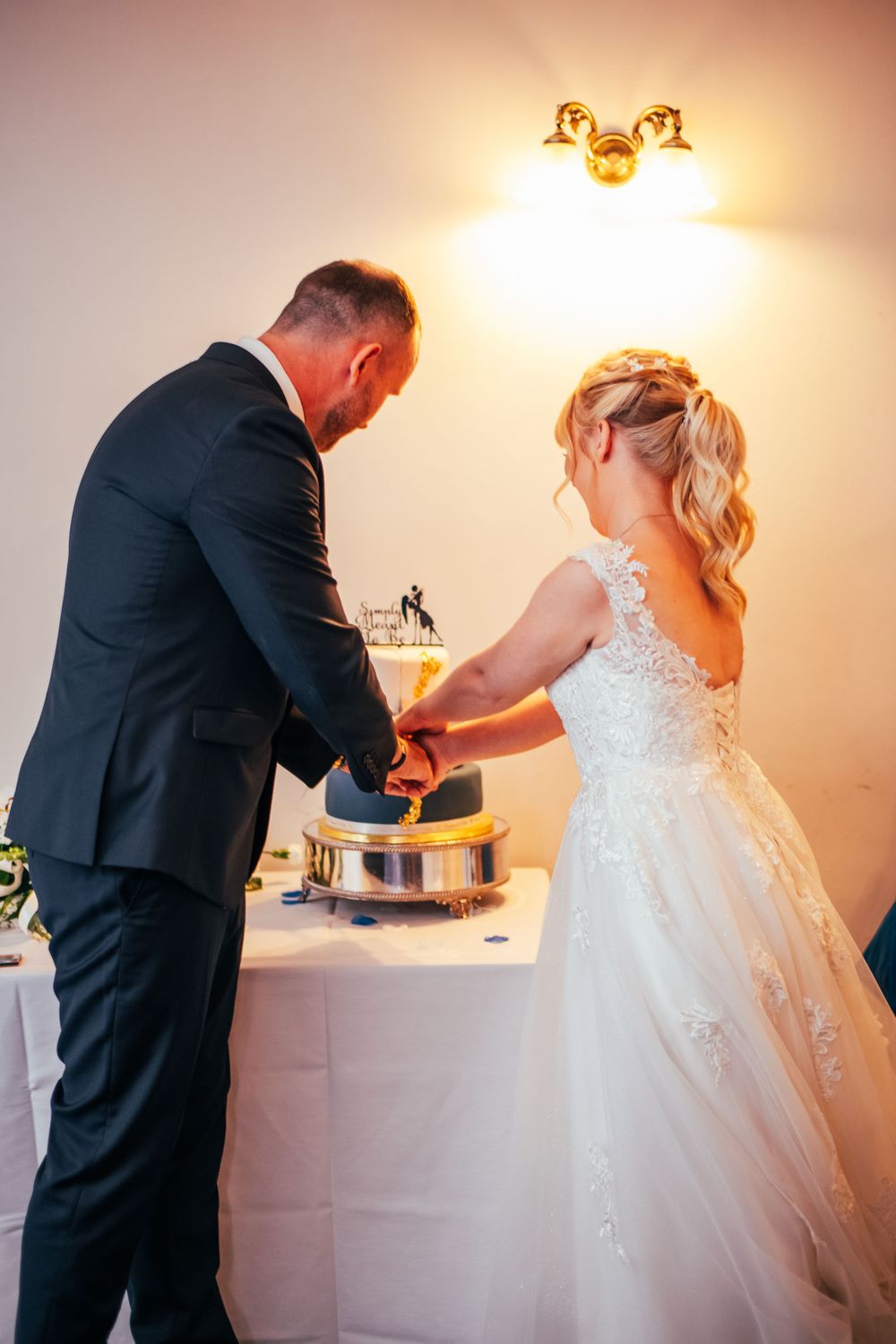 A wedding couple cuts their cake together during their reception celebration.