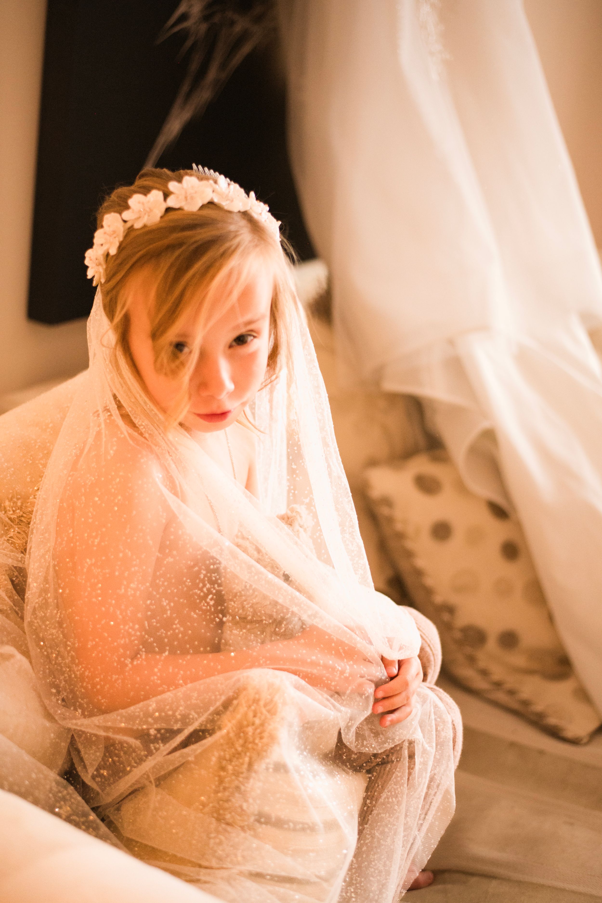 A dreamy bridal portrait with soft lighting showing a bride wrapped in her veil.