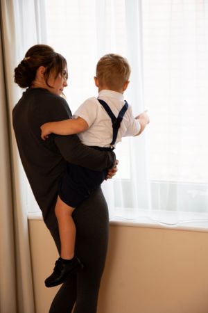 A tender moment between parent and child looking out a bright window together.