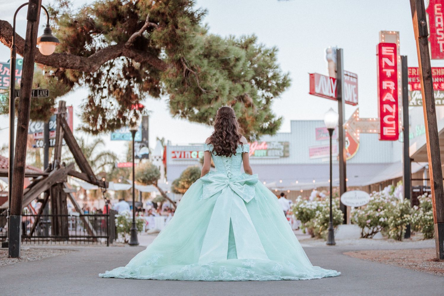 A stunning mint green quinceañera dress photographed on a city street with neon signs.