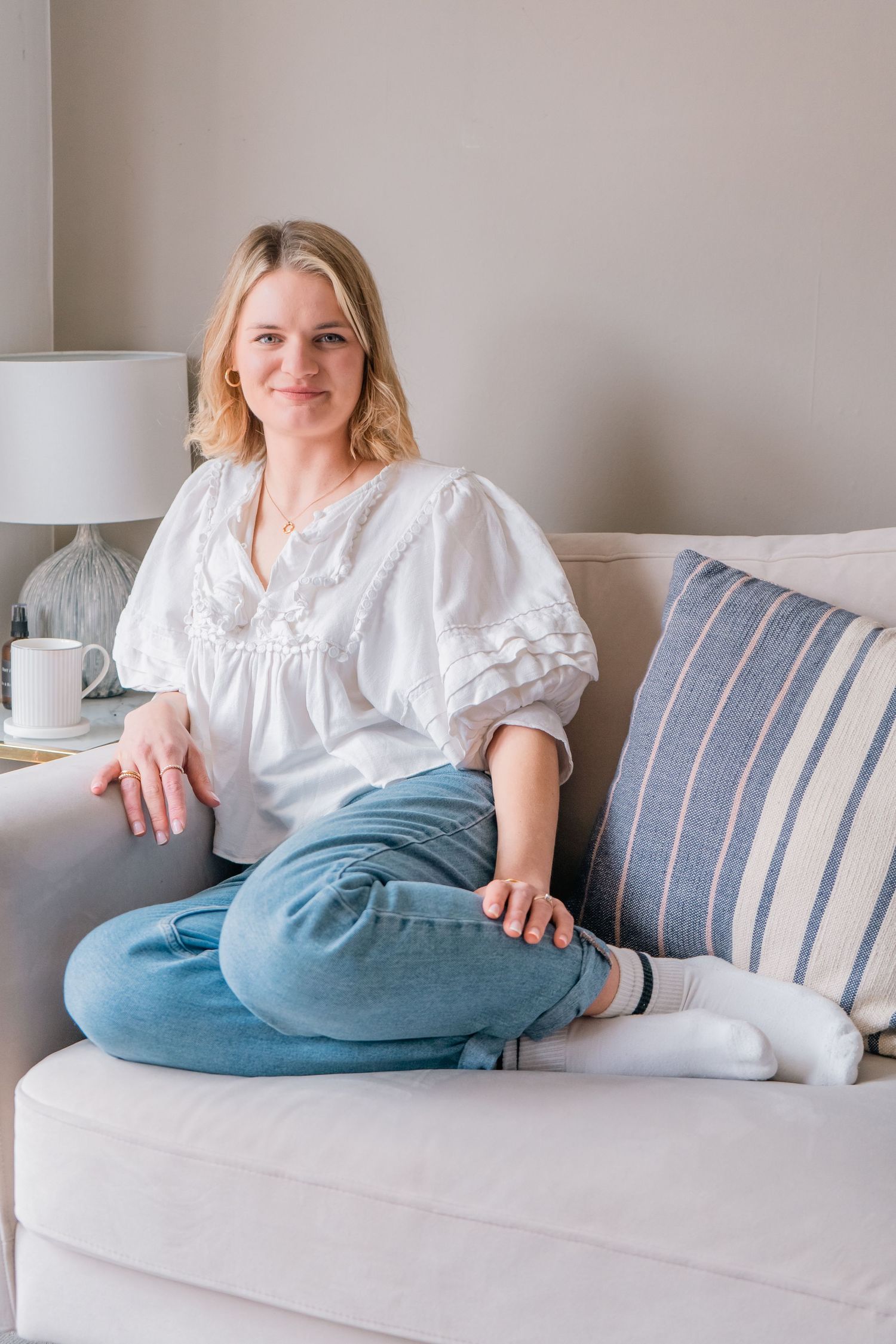 Person in white blouse relaxing on striped couch cushions.
