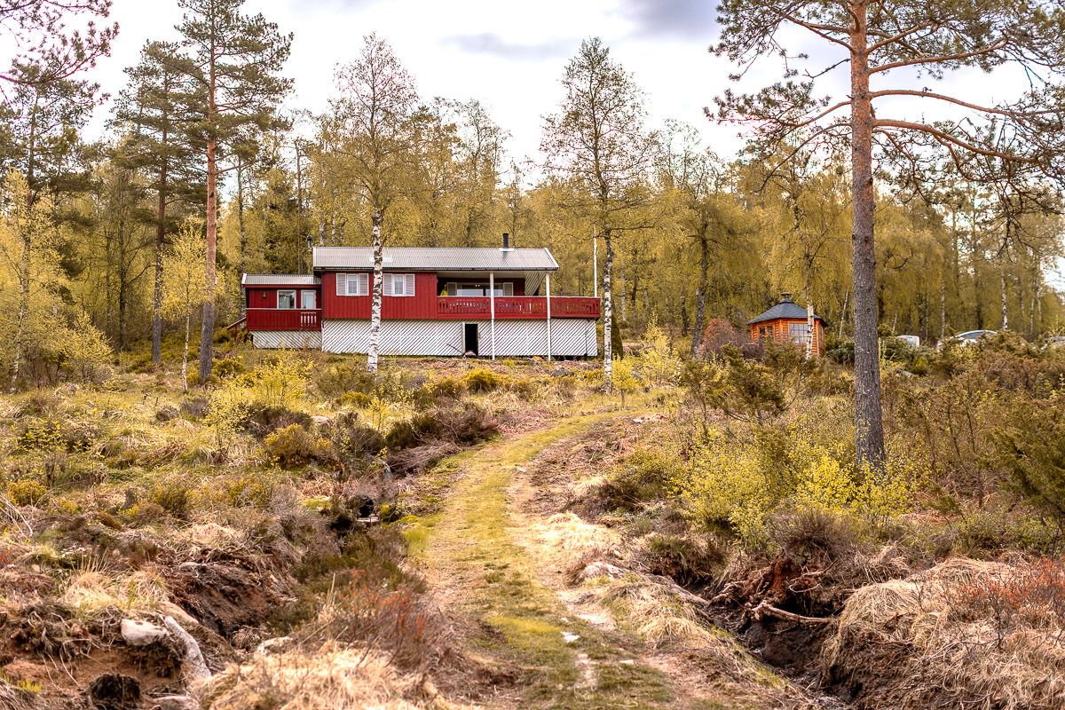 Rød og hvit hytte på Naglestad i Agder, bygd i 1994. Mye natur rundt.