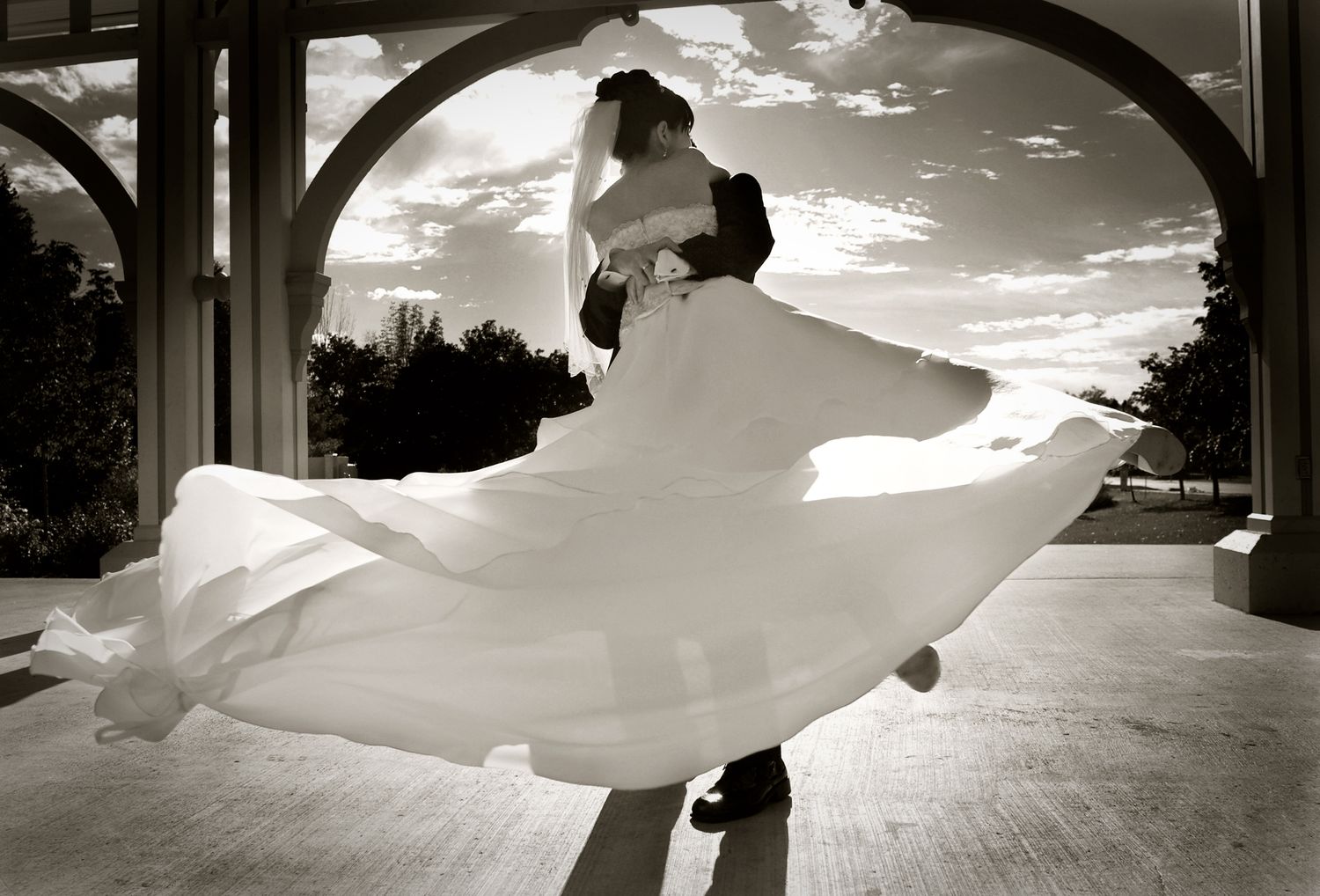 Black and white photo of a dancing couple with bride's dress twirling dramatically.