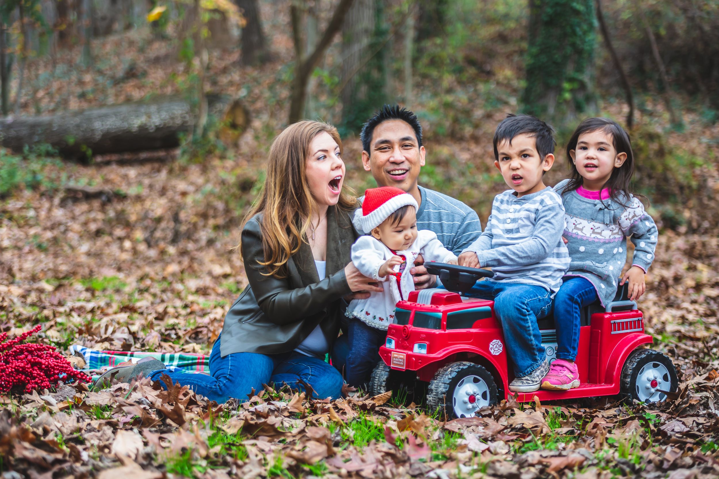 Family with children posing together outdoors in a park.