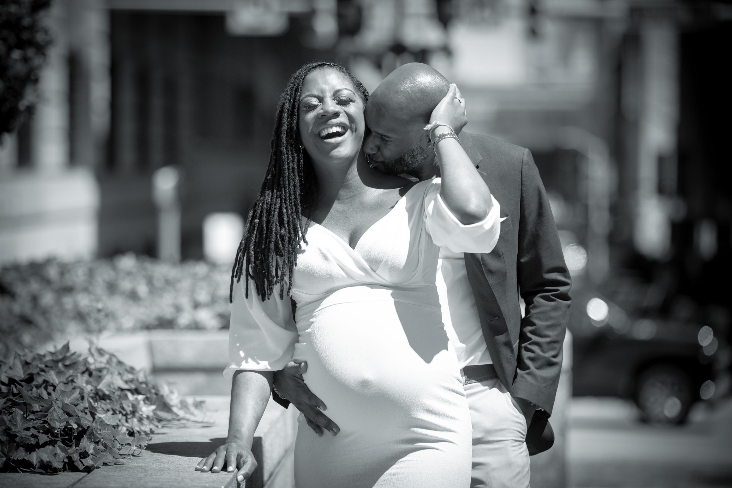 Pregnant couple posing together outdoors in a park.