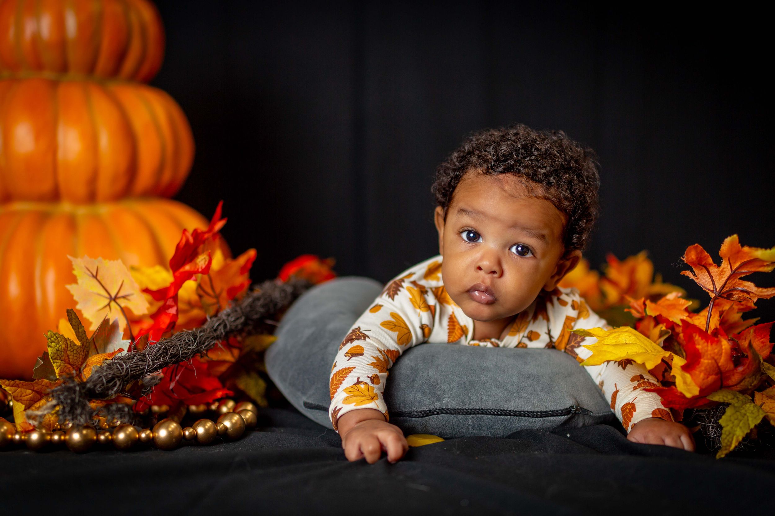 Baby portrait sitting among pumpkins at a fall themed setup.