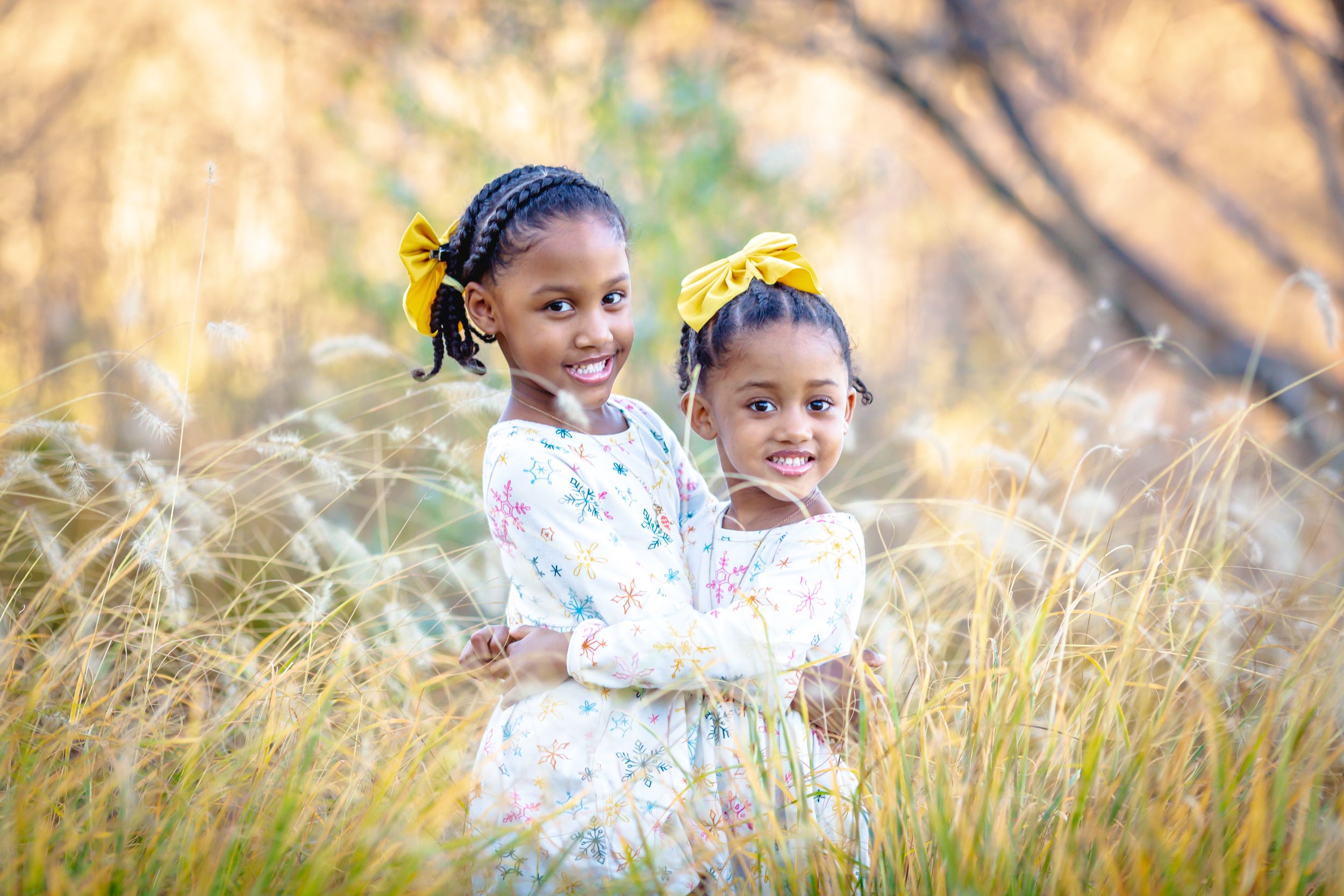 two girls hugging together in a field outdoors.
