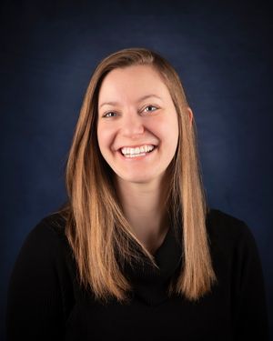 Studio portrait of woman smiling with a dark blue background.