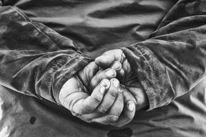 Close up image of a man's holding his hands behind his back in black and white.