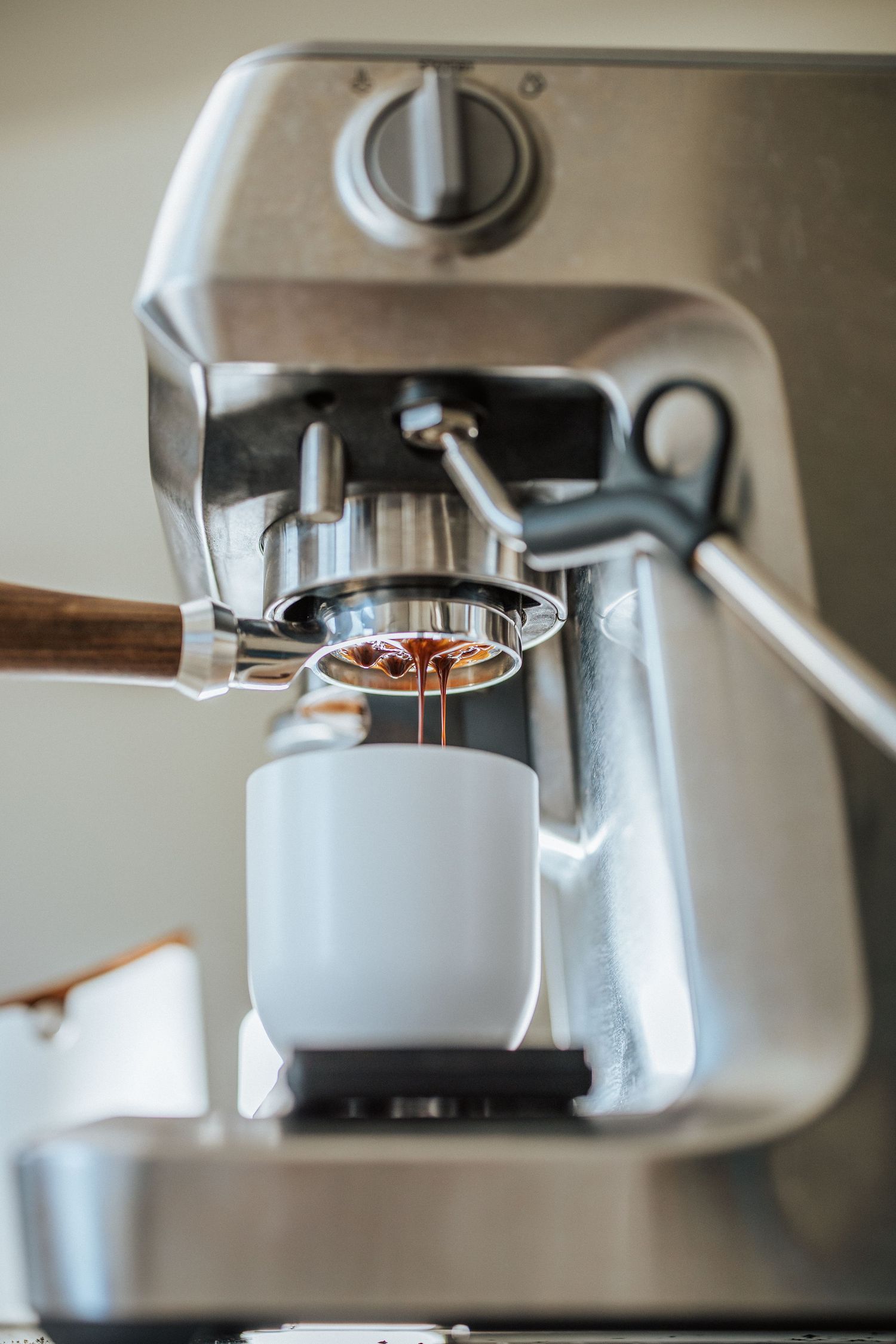 Close-up sequence showing espresso being extracted from a commercial coffee machine's portafilter into a cup.