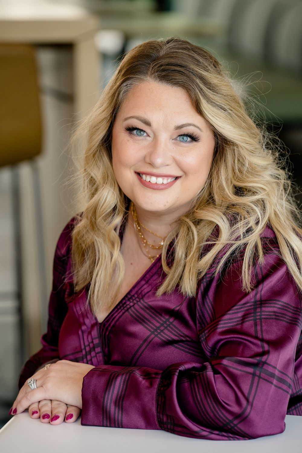Professional indoor portrait session featuring a bright smile and plum colored satin blouse.