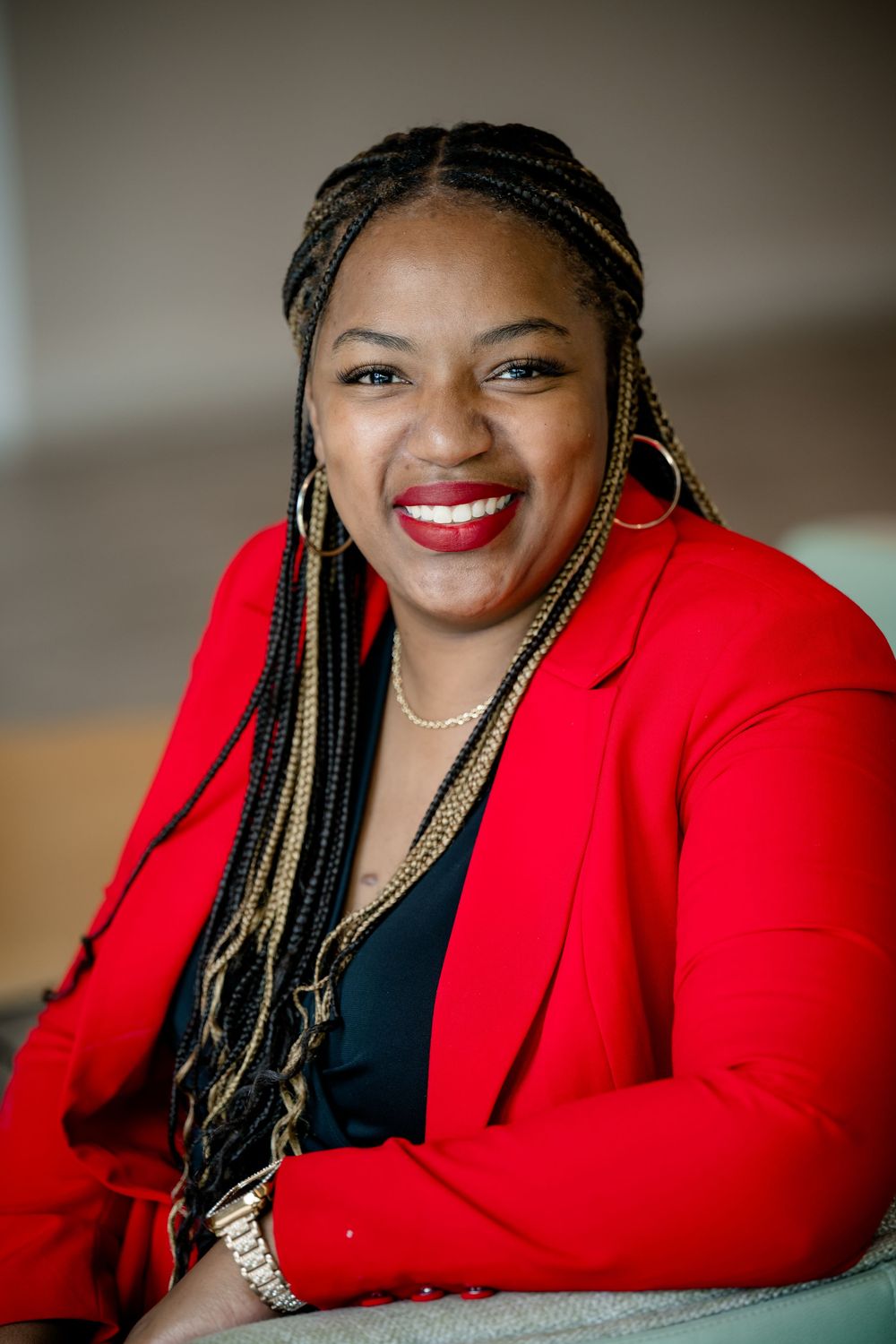 A series of professional headshots showing a person in a vibrant red blazer with braided hair and warm smile.