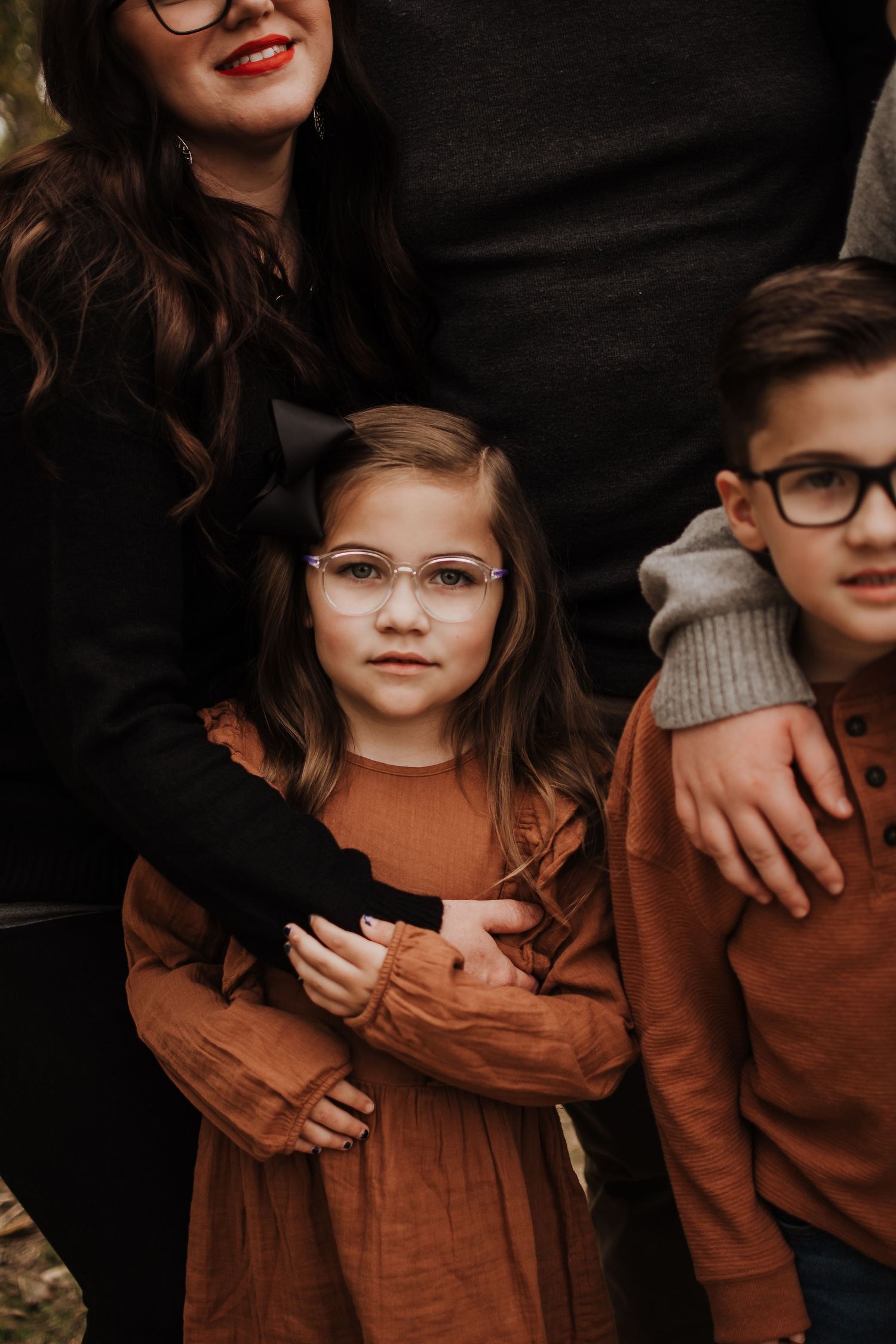 Row of six connected photos showing children wearing matching brown corduroy outfits and glasses against dark background.