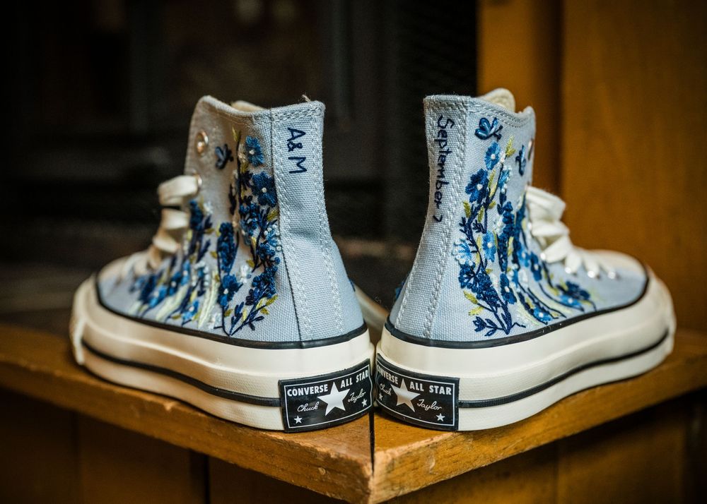 Pair of custom painted blue and white high-top Converse sneakers displayed on wooden surface.