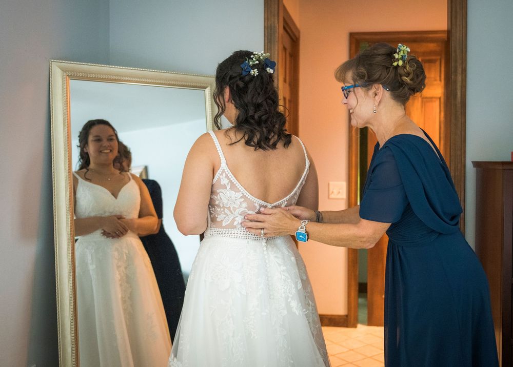 Wedding party gathers for preparation as bride gets ready in elegant white gown with navy blue bridesmaids.