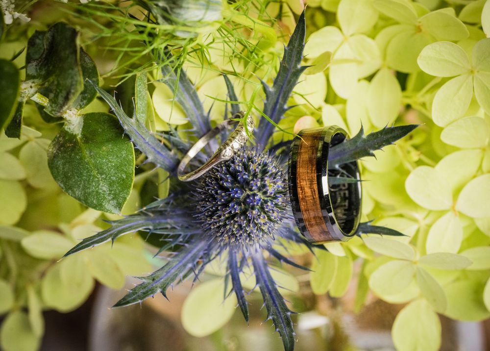 Floral arrangements with white and yellow blooms accent a rustic wedding ceremony setting.