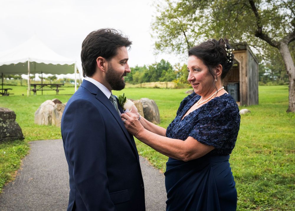 Couple standing together outdoors with green grass and trees in background during an intimate moment.
