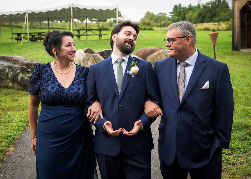 Wedding party members in navy blue attire share candid laughs and interactions during outdoor photo session.