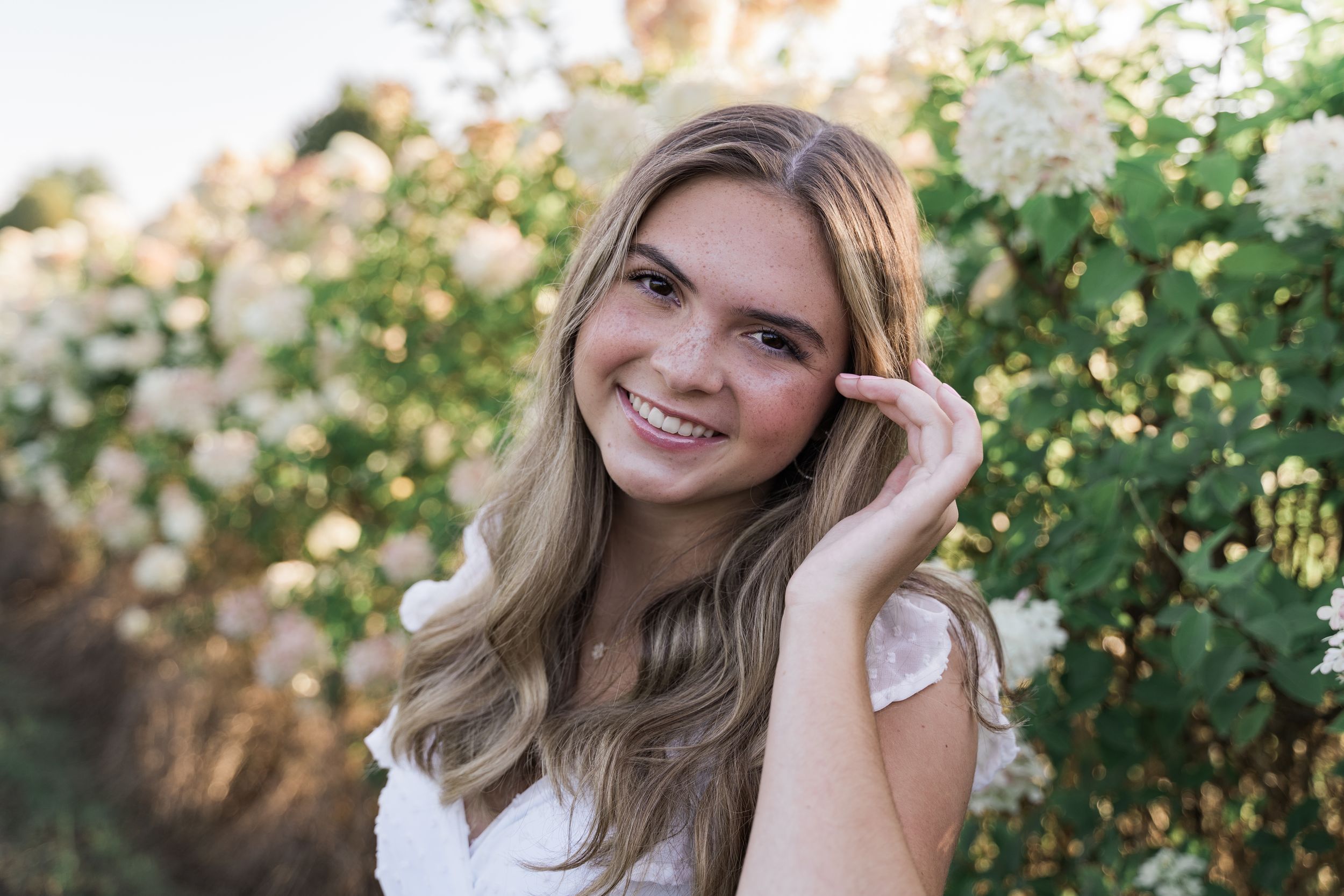 Portrait session in a lush garden setting with natural sunlight filtering through green foliage.