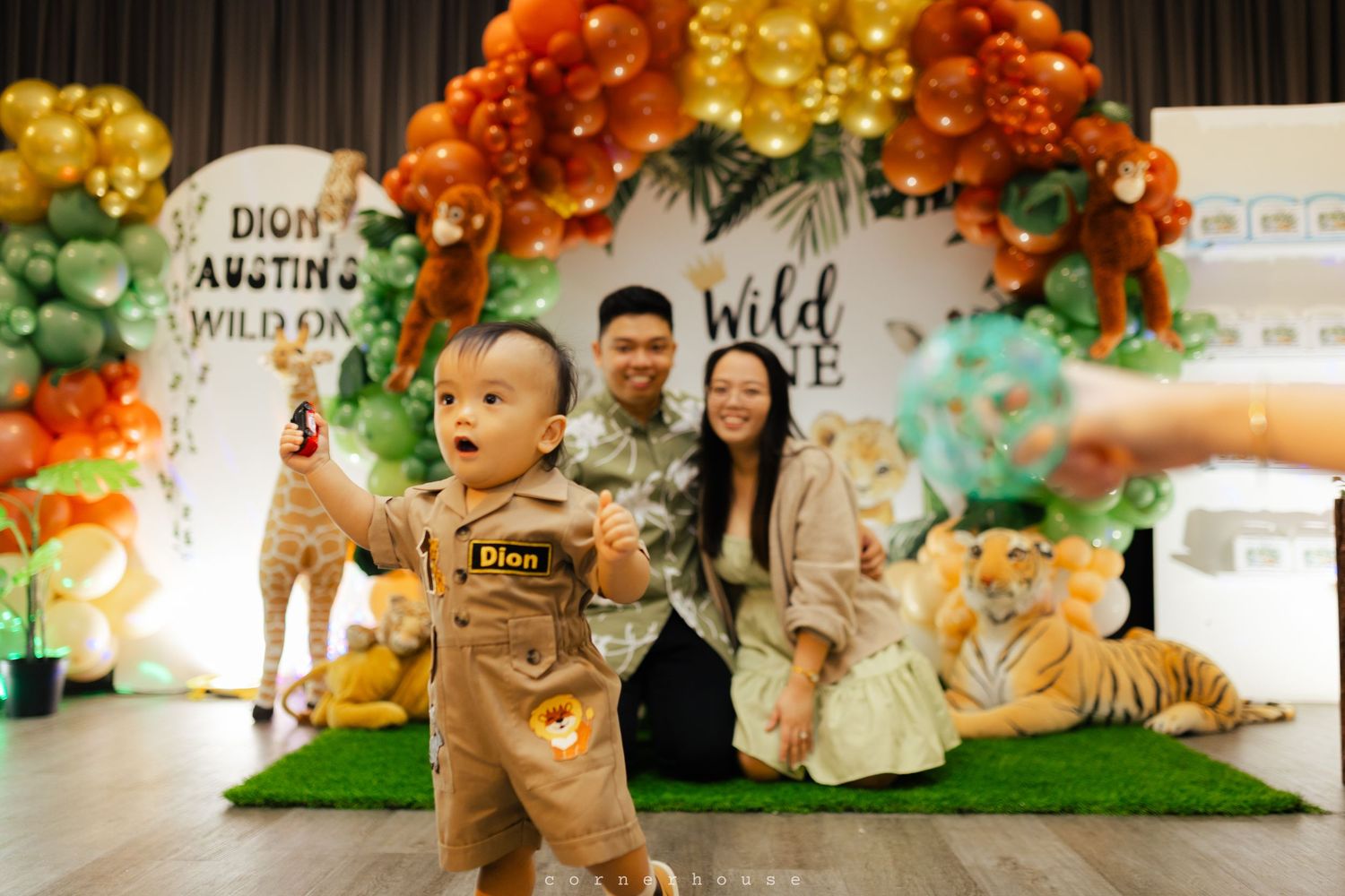 Festive fall-themed birthday party setup with orange and gold balloon garlands and decorative autumn elements in an indoor space.