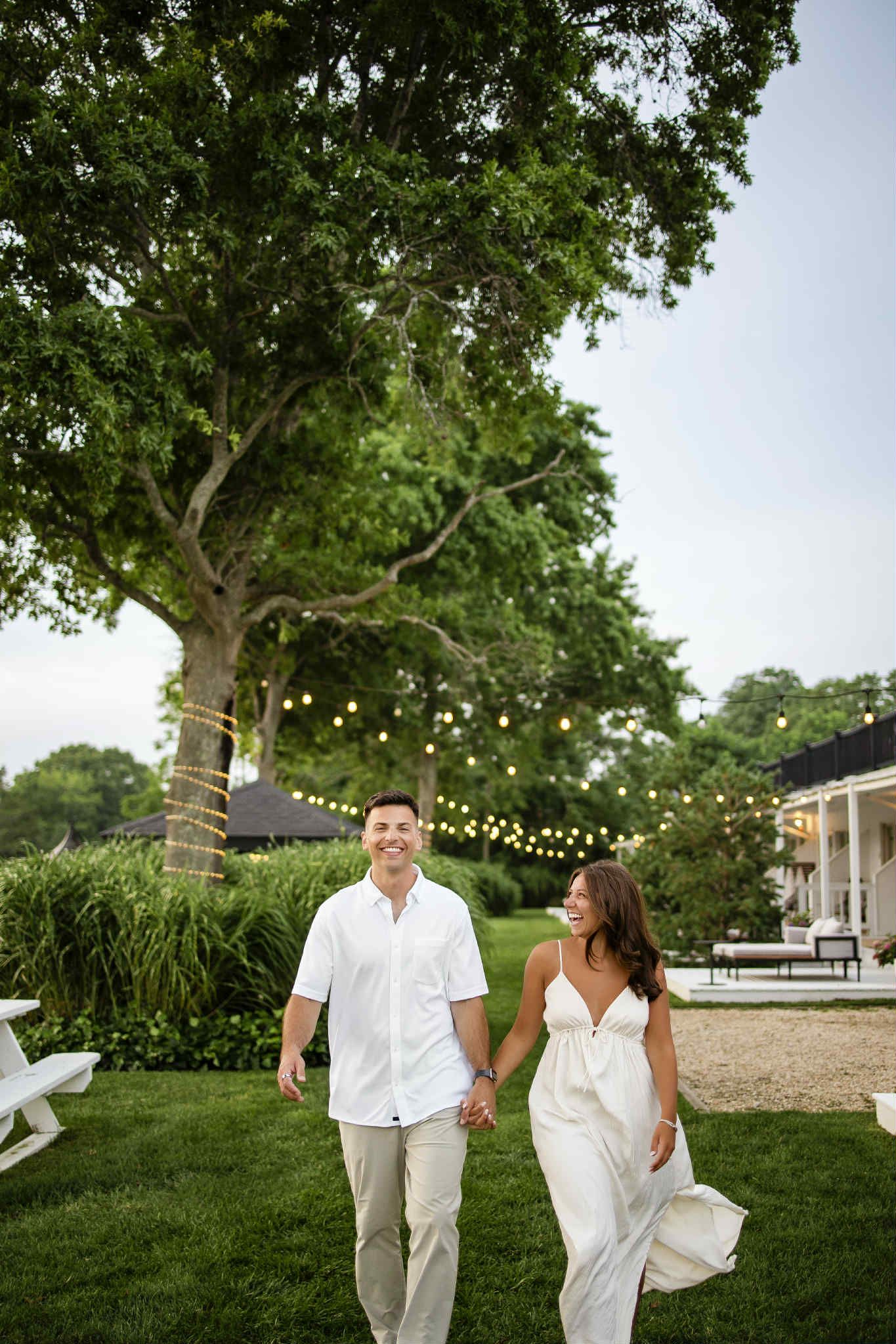 A romantic proposal scene set between rows of grapevines in a scenic vineyard with white flowers and a blanket.