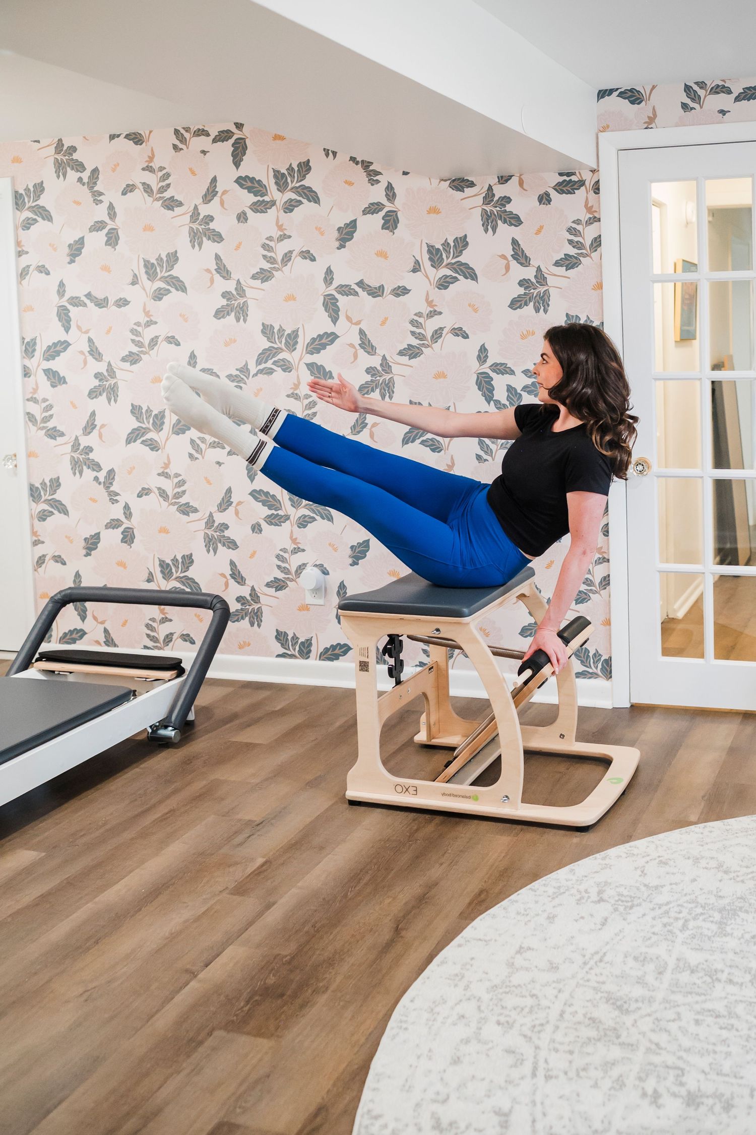 Rows of wooden bookshelves lined with colorful books stretch down a warmly lit bookstore aisle with hardwood floors.