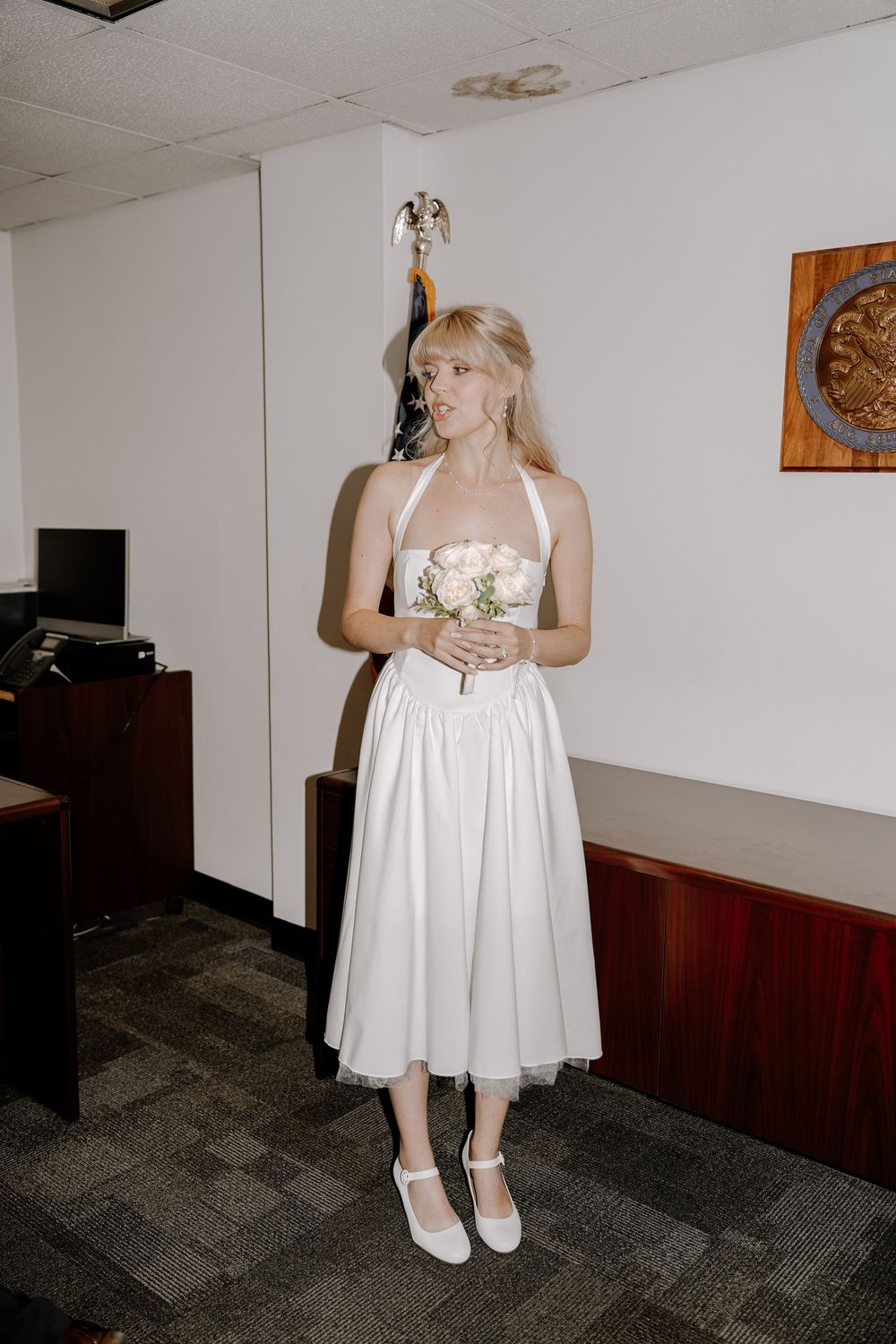 A person in a short white dress and white shoes poses in an office setting across multiple film-style shots.