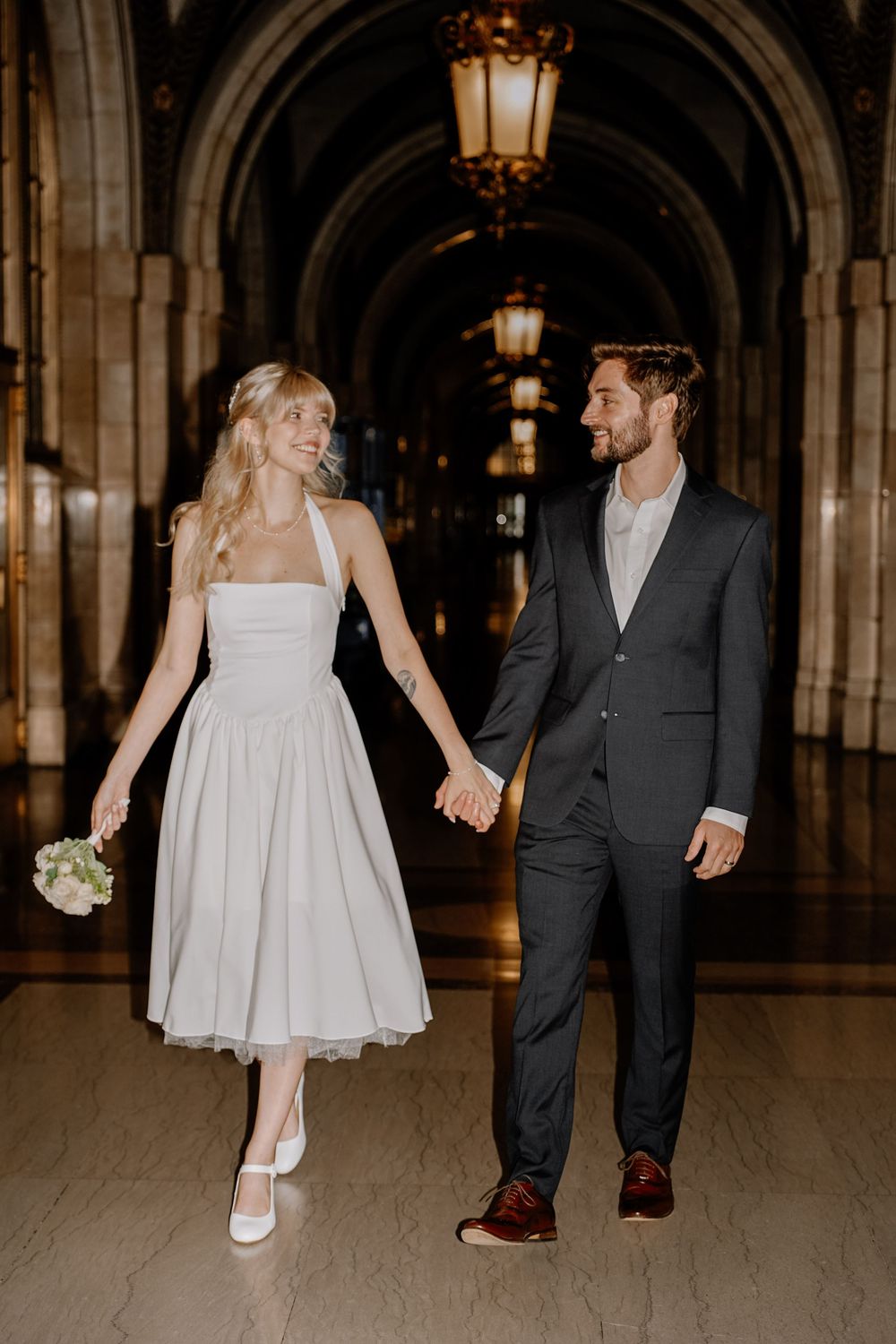 Romantic wedding photo series showing a couple dancing and walking in a beautiful vaulted hallway.
