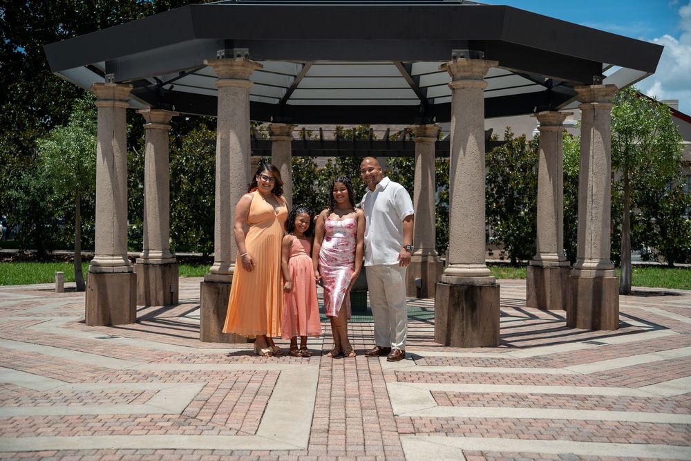 Wedding party group photo under elegant stone gazebo with columns, Tampa outdoor wedding photography in landscaped setting.