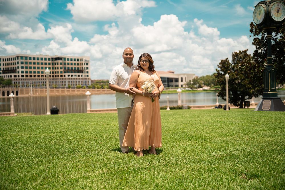 Bridesmaids in peach dresses celebrating together on grassy hill, Tampa wedding photography under blue Florida skies.