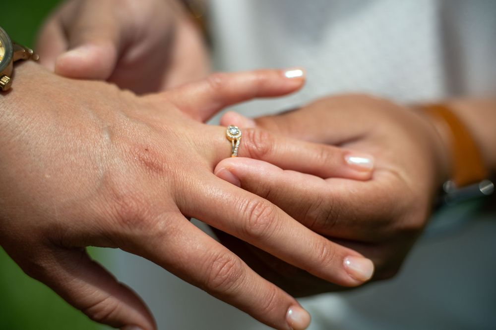 Close-up of hands with elegant gold engagement rings, romantic wedding photography in Tampa, Florida.