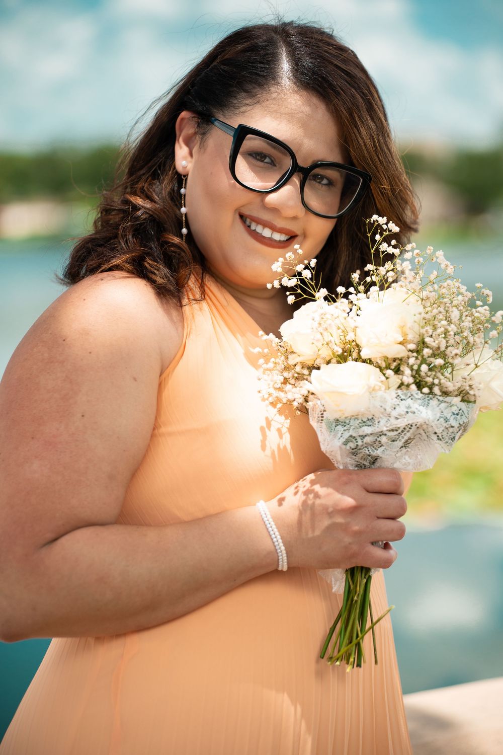 Bridesmaid in peach dress holding baby’s breath flowers, Tampa wedding photography outdoors in Florida sunshine.
