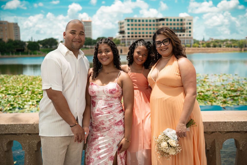 Family and friends group photo by lake with water lilies, Tampa waterfront, bright sunny wedding photography.