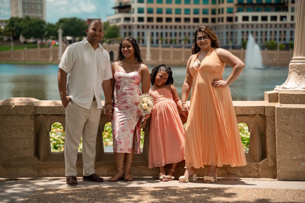 Wedding photoshoot in Tampa, Florida — bridal party in peach and coral dresses posing on a stone balcony overlooking the lake.