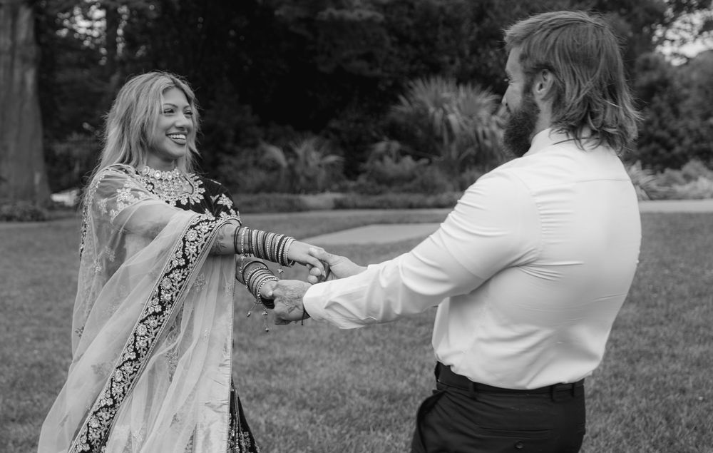 A couple dancing together outdoors in black and white, with her dress flowing as they spin.