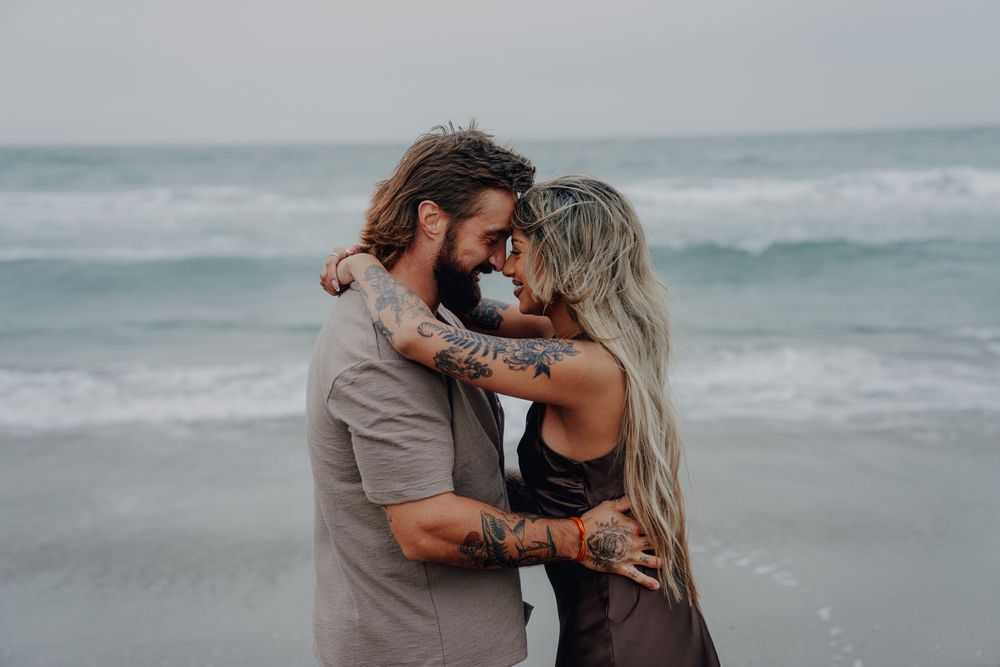 Romantic couple embracing on a misty beach in a series of candid moments at sunset.