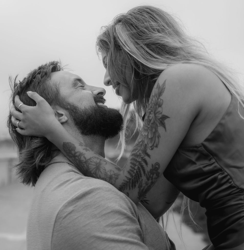 A couple sharing an intimate moment outdoors in black and white photography.