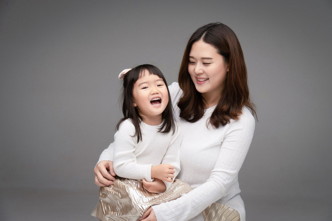 Two people embracing and laughing together in a black and white photoshoot series.